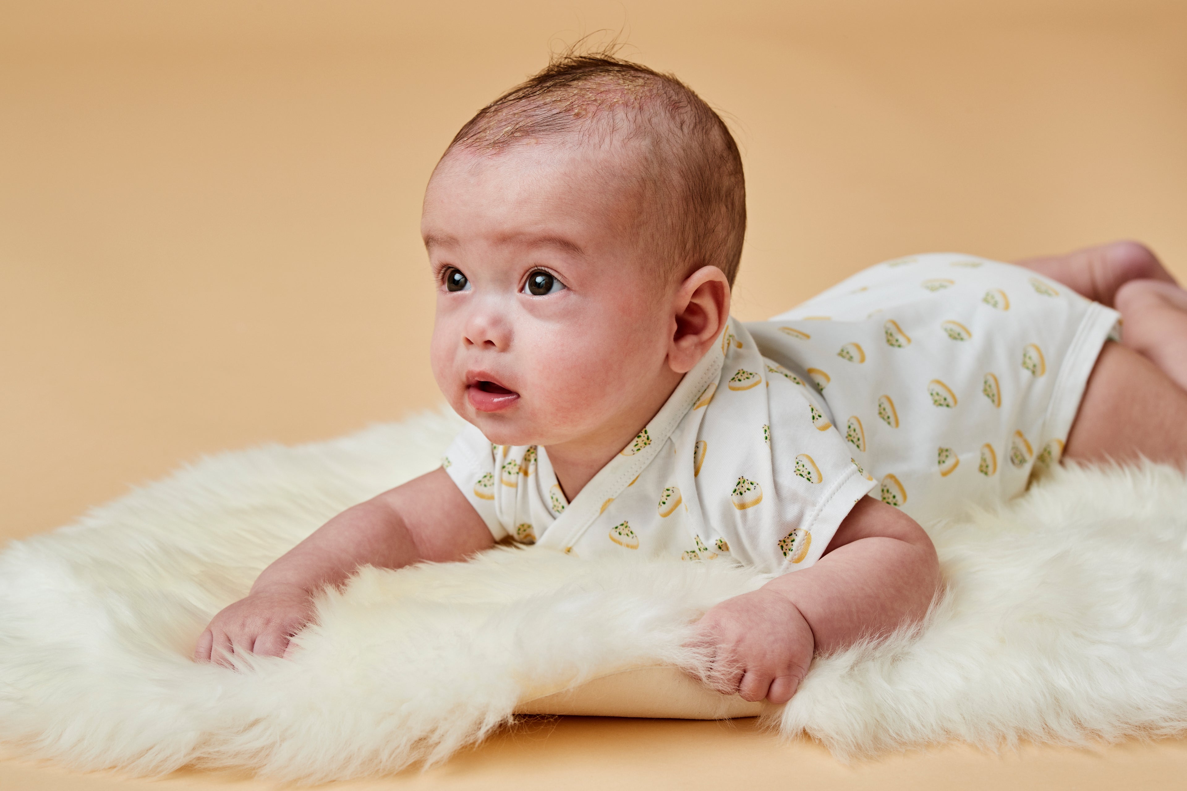 Baby with dumpling bodysuit on sheepskin rug